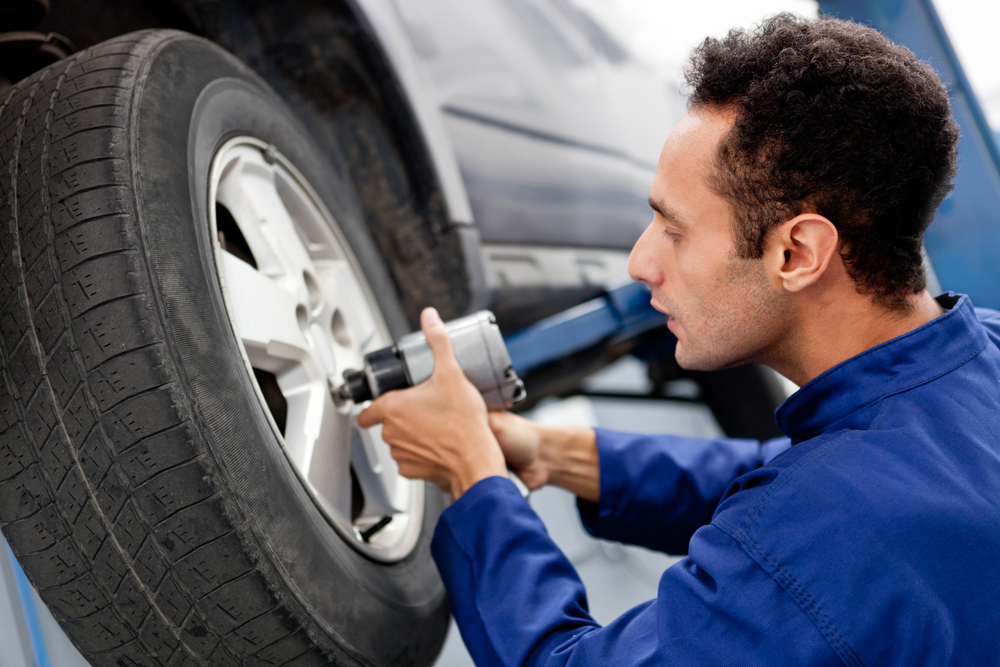 Male mechanic at a car garage fixing a wheel